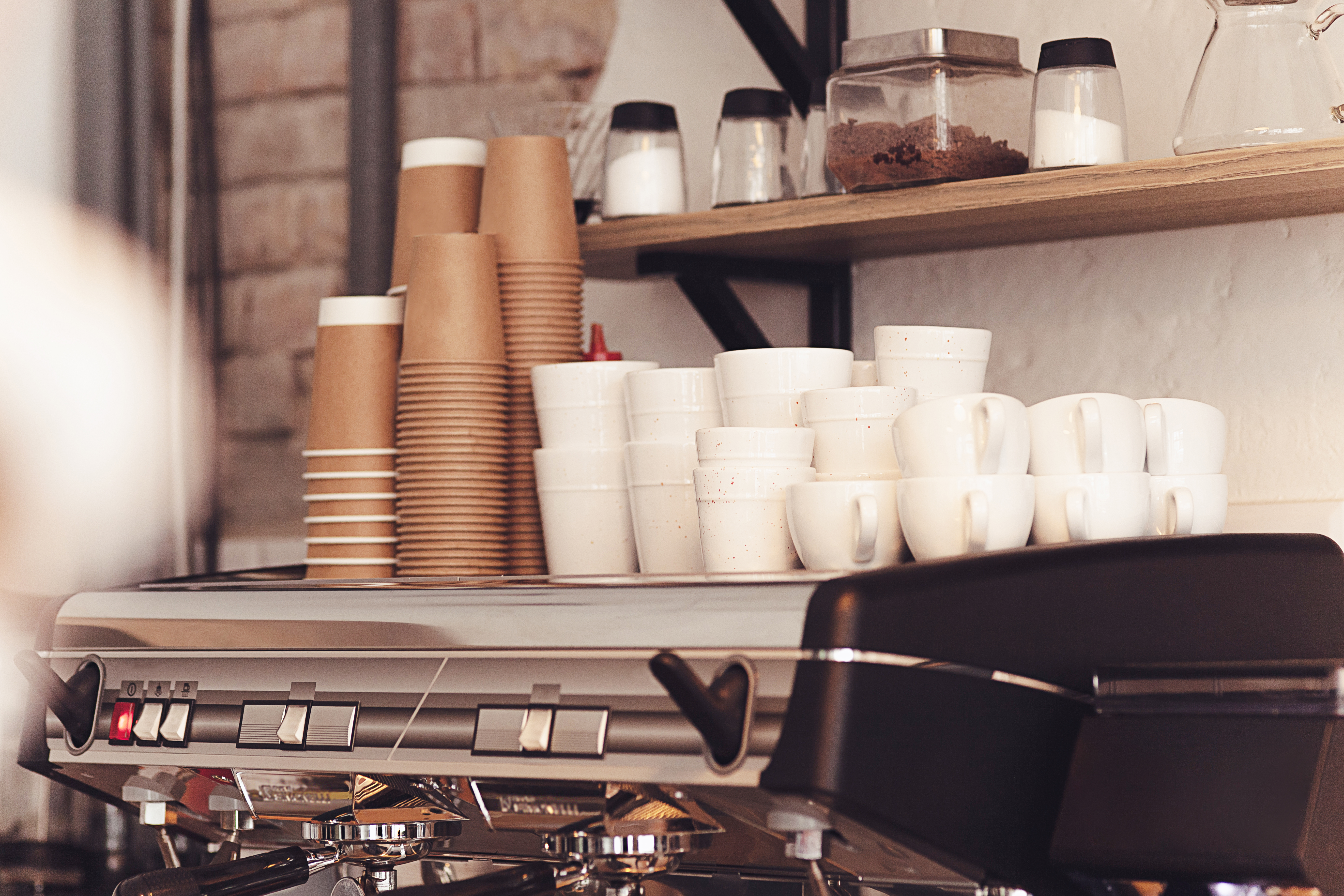 Disposable coffee cups stacked on top of an espresso machine.