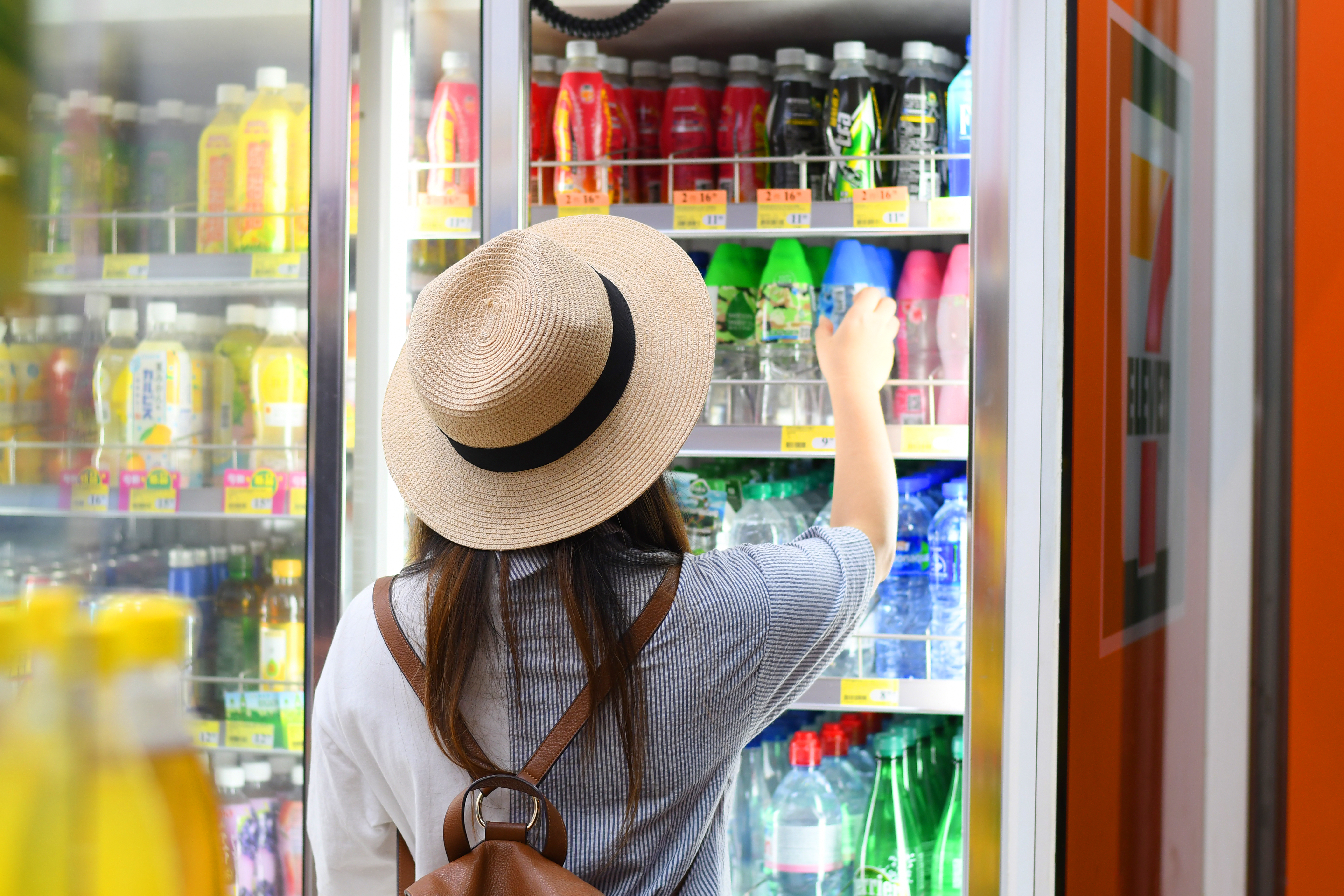 A woman standing in front of a refrigerator in a Chinese 7-Eleven