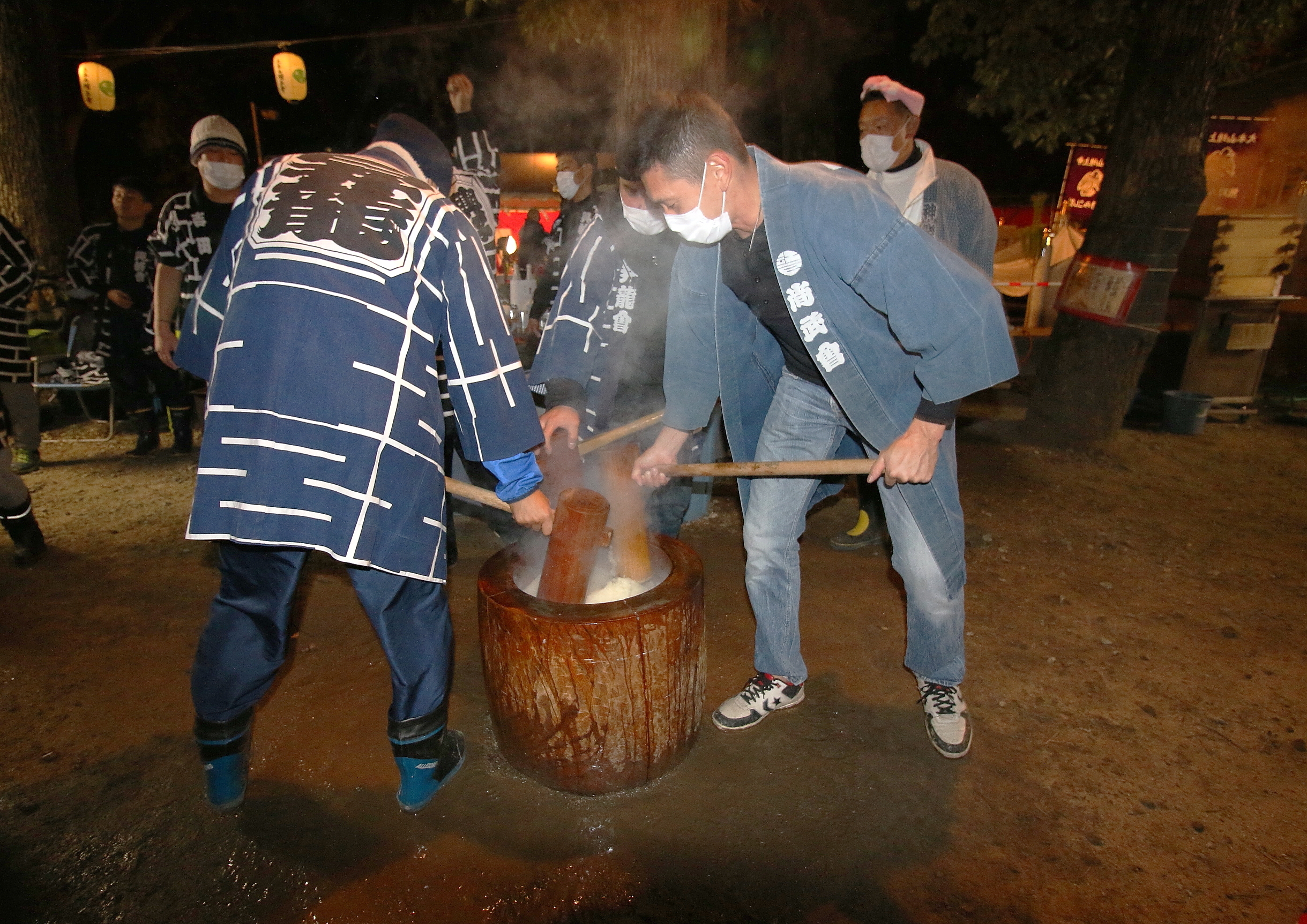 Men pound mochi with a mortar and pestle