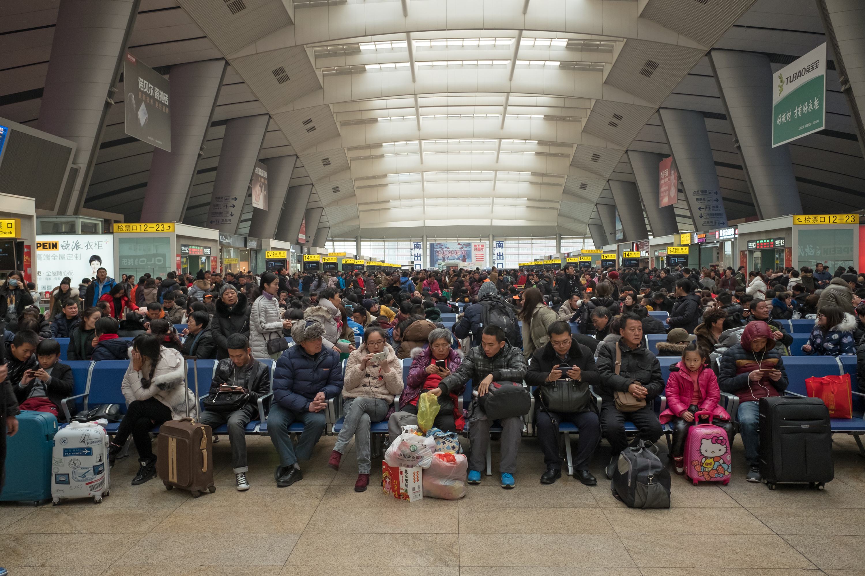 travelers wait in crowded Beijing train station